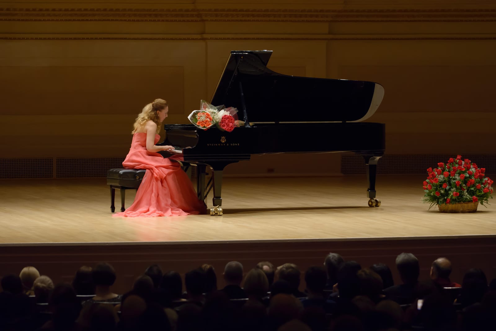 The house seen past the piano, Katya Grineva in the coral gown playing to a full auditorium
