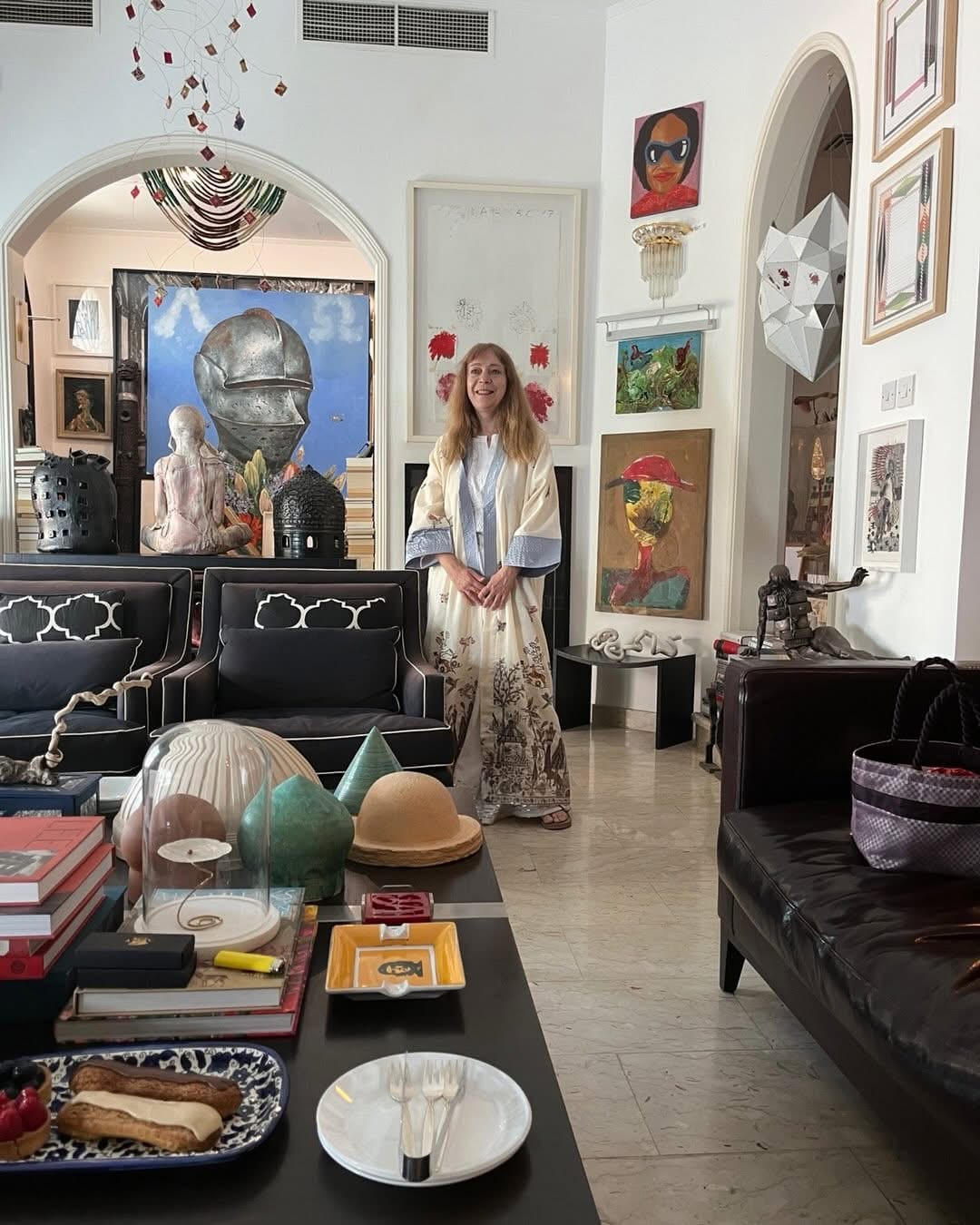 Katya Grineva in India, standing in a room hung with paintings and filled with sculpture